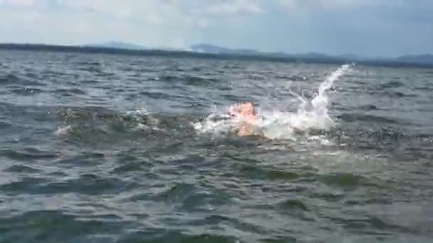 Un bărbat înoată ridicând un spray cu apă . — Videoclip de stoc