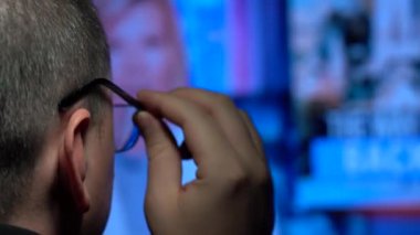 Hızlı haber yayını. Arkadan bak. Gözlüklü bir adam ekrana bakıyor. Medya aracılığıyla bir kişi için büyük miktarda bilgi..