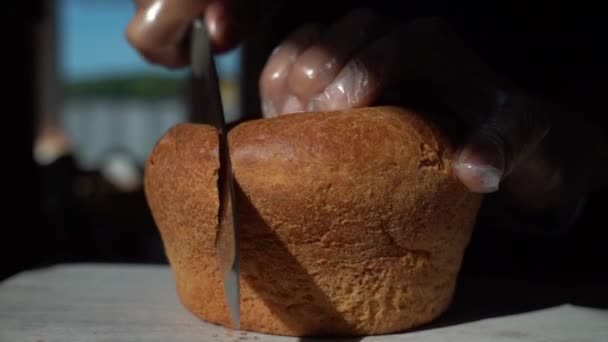 Taglia una fetta di pane. Pane fresco su un tavolo vicino alla finestra primo piano, illuminato dal sole del mattino. Il concetto di alimentazione sana e cottura tradizionale — Video Stock