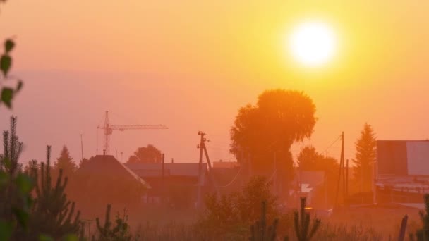 Ende des Arbeitstages in ländlichen Gebieten. Straße am Dorfrand. Die Sonne versteckt sich hinter der Krone eines Baumes. — Stockvideo