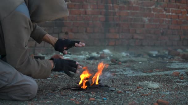Bezdomovec si ohřívá ruce. Ruce v černých roztrhaných rukavicích. Post-apokalypsa scéna — Stock video