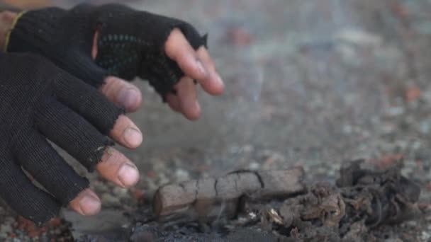 Homeless man warms his hands. Hands in black torn gloves Close up. Post-apocalypse scene — Stock Video