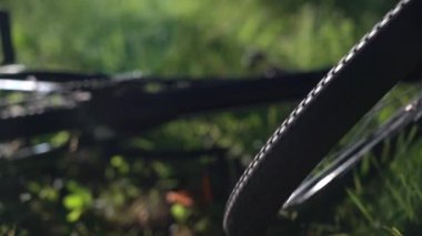 Bisikletten düştükten sonra. Bisiklet sürerken kaza. Dağ bisikleti tekeri dönüyor. Dağ bisikleti düştü, ön teker dönüyor. Yeşil çimenler. Seçici odak.