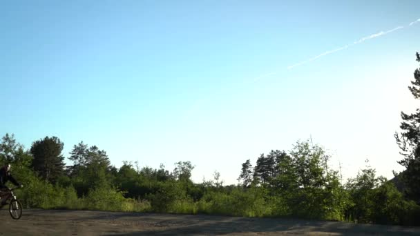 Avond fietstocht. Fietser met een rugzak op een achtergrond van blauwe lucht. Rijdend bij zonsondergang. Fietser Cardio. Landelijke fietstochten — Stockvideo