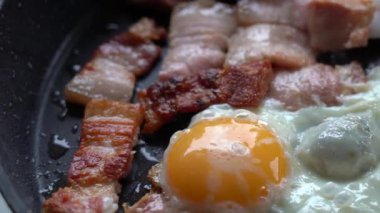 Yumurta ve pastırma kızartma tavasında pişiriliyor. Kızartma tavasında pastırma ve yumurta parçaları, yakın plan. Pencereden gelen Doğal Işıklandırma