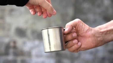 Dilenciye bozuk para ver. Yardım eli uzatıyorum. Metal bardaklı yaşlı bir adamın eli. Gün ışığı
