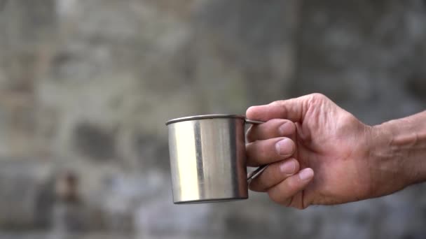 Pede dinheiro. A mão de um velho mendigo com uma caneca pede esmola. Close-up. Luz do dia — Vídeo de Stock