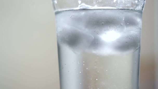 Sprankelend mineraalwater in een glas met ijs.Lichte ondergrond. Daglicht. Close-up — Stockvideo