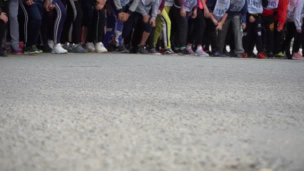 Deportes juveniles masivos corriendo. Piernas de jóvenes corredores al comienzo de una maratón. Movimiento lento — Vídeos de Stock
