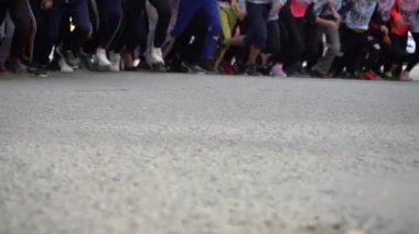 Koşu maratonunun başında koşan genç koşuculardan oluşan bir bacak. Toplu gençlik sporları koşuyor. Ağır çekim. Kalabalık koşmaya başlar.