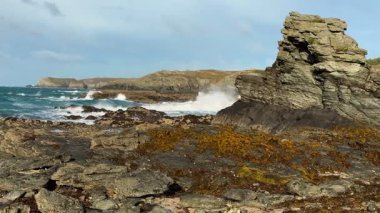 Kuzey Galler 'in Gwynedd adasındaki Anglesey Adası' nda Trearddur Körfezi kıyısında dalgalı bir deniz..