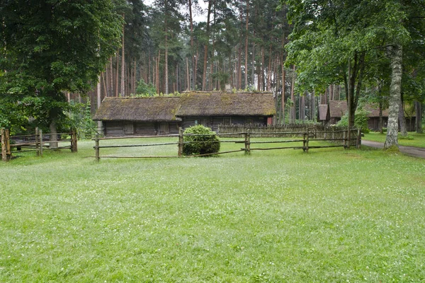 Ancienne maison en bois avec toit en roseau et clôture en bois — Photo