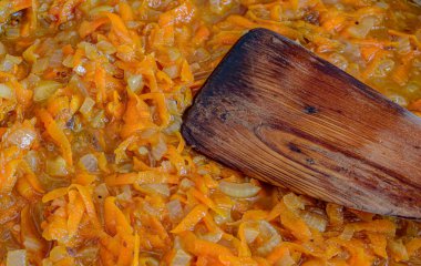 Pişirmek için havuç, soğan ve ahşap bir spatula.