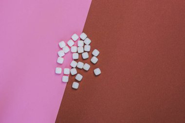 Pembe ve kahverengi arkaplan üzerinde beyaz kare haplar yakın plan kopyalama alanı