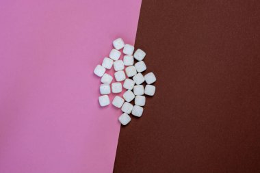 Pembe ve kahverengi arkaplan üzerinde beyaz kare haplar yakın plan kopyalama alanı