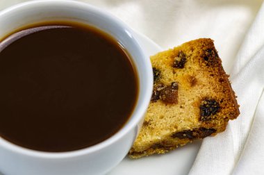 Bir fincan kahve ve yatakta bir parça kek kahvaltısı.