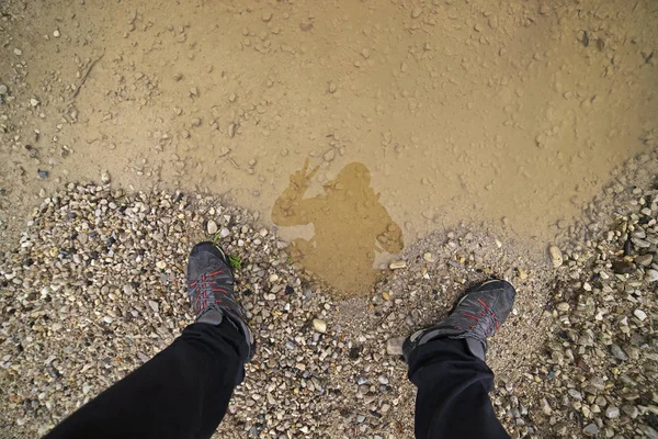 The person takes selfies on the reflection in the puddle