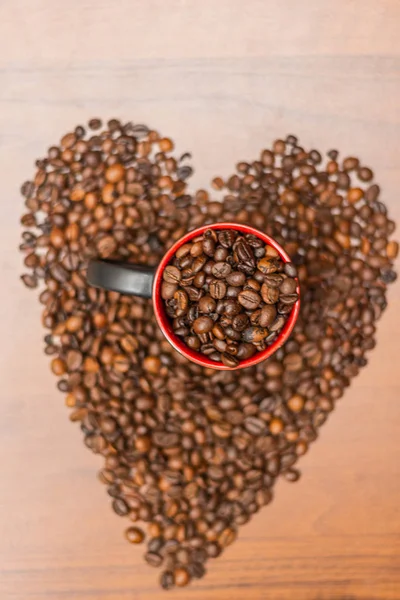 A cup of coffee with fried beans in the shape of a heart. Top view with copy for text