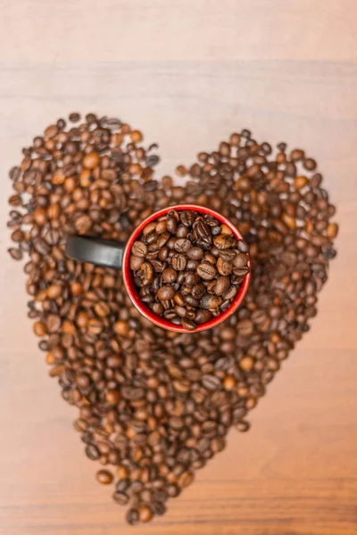 A cup of coffee with fried beans in the shape of a heart. Top view with copy for text