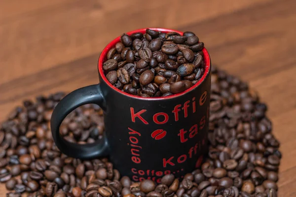 A cup of coffee with fried beans on a wooden background. Top view with copy for text