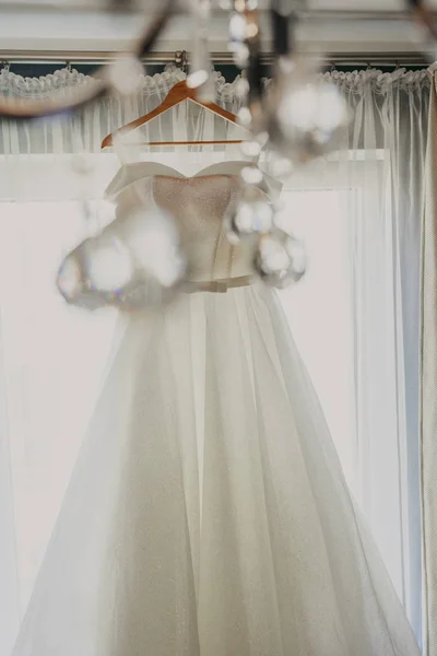 Свадебное платье. Белое свадебное платье с полной юбкой на вешалке в комнате невесты с белыми занавесками. Свадебные атрибуты. Нет людей . — стоковое фото