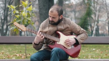 Parkta elektro gitar pratik genç bir müzisyen, sol el gitarist, sakallı Kafkas, 4k stok görüntüleri, 23.976 fps