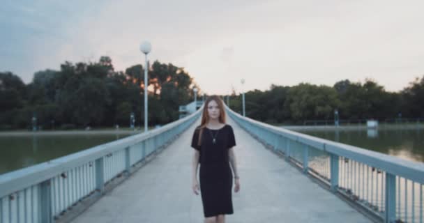 年轻女子鼻子穿孔穿黑色走在桥上的相机在慢动作 — 图库视频影像
