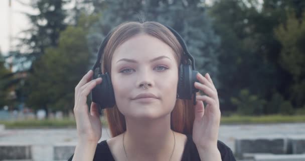 Chica Quita Los Auriculares Inalámbricos Negros Mira Cámara — Vídeos de Stock