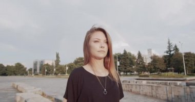 Burun piercing ve siyah t-shirt ile Kahverengi saçlı genç kadın onu güneş gözlüğü koyar - göz kamaştırıcı güneş ışığı ve arka planda gökkuşağı