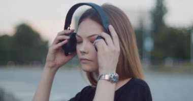 Güzel kahverengi saçlı kız büyük siyah bluetooth kulaklıkmüzik dinler