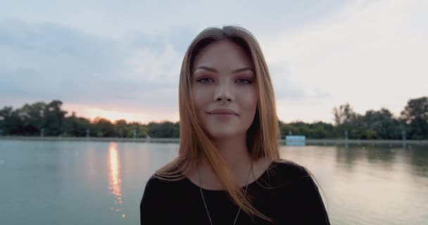 美しい若い女性は 日没時に美しいサイトでカメラに微笑む クローズアップ — ストック動画
