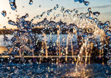 Bir çeşmenin akıntısı su sıçratır, günbatımı