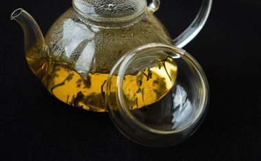 Bir kase ve bir çaydanlık koyu arka planda yeşil çay, yakın plan.