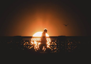 Gün batımının arka planında yaşlı bir adamın silueti. Kocaman bir güneş..