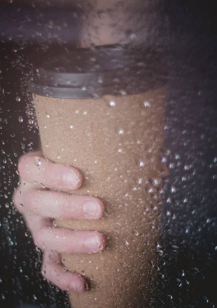 Enjoying coffee on rainy day. Coffee time on rainy day.Wet glass window and cup of hot caffeine beverage.Autumn mood.