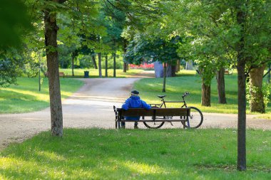 Madrid, İspanya 'da bir parkta bisikletinin yanında oturan yaşlı bir adam.