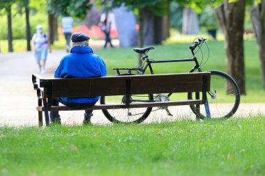 Madrid, İspanya 'da bir parkta bisikletinin yanında oturan yaşlı bir adam.