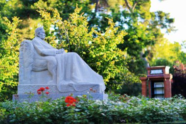 Madrid, İspanya - 16 Haziran 2020: Madrid, İspanya 'daki Retiro parkında yazar Benito Perez Galdos' un heykeli. Arka planda halk librar 'ı