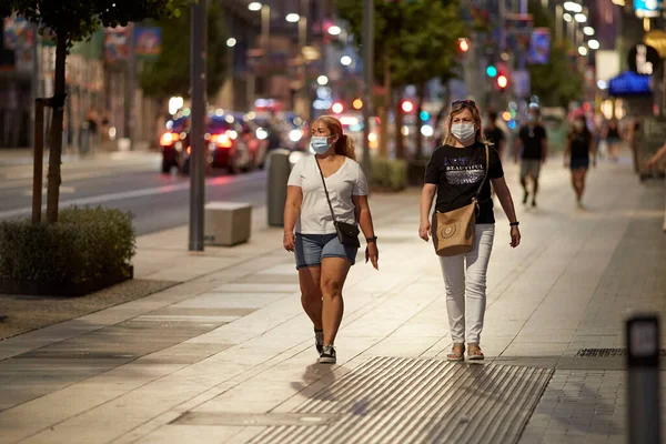Madrid, İspanya - 8 Ağustos 2020: Madrid şehrinde gün batımında gezen turistler ve aylaklar. İnsanlar kendini Covid-19 'dan korumak için maske takıyor.