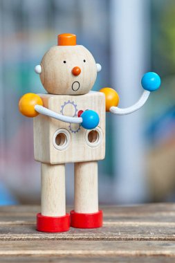 Kırmızı kalpli ve sürpriz suratlı tahta oyuncak robot. Odaklanmamış arkaplan.
