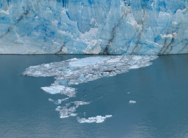 Iceberg. The Wall of Blue Ice. Small Pieces of Ice Floating on Surface of the Water.  Blue Ice Packs. Sunlight Delicately Reflecting in the Blue Wall of the Glacier.