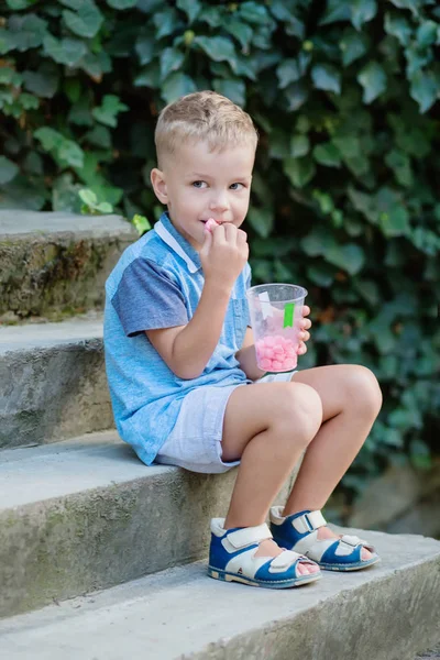 可爱的小男孩吃着一个美人鱼坐在台阶上的夏天 — 图库照片