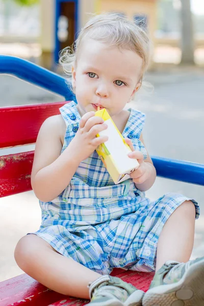 Pequeno Bebê Bonito Beber Suco Uma Palha Enquanto Sentado Banco — Fotografia de Stock