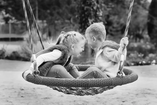 秋の日 黒と白のスイングで楽しんで幸せな幼い子ども — ストック写真