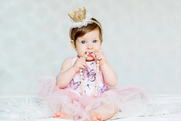 迷人的蓝眼睛女婴礼服和皇冠与珍珠 图库图片