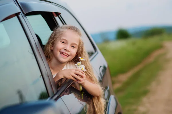 Счастливая Маленькая Девочка Машине Выглядывает Окно Букетом Ромашки — стоковое фото