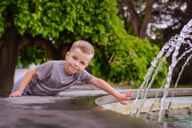 Yaz aylarında bir çeşme ile oynayan sevimli küçük çocuk