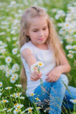 Baharda papatya tarlasında gülümseyen tatlı küçük kız.