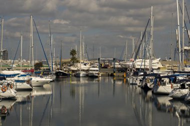 Kıbrıs Rum Kesimi 'nde bulutlu gökyüzü ve su yansımaları olan bir marina manzarası 