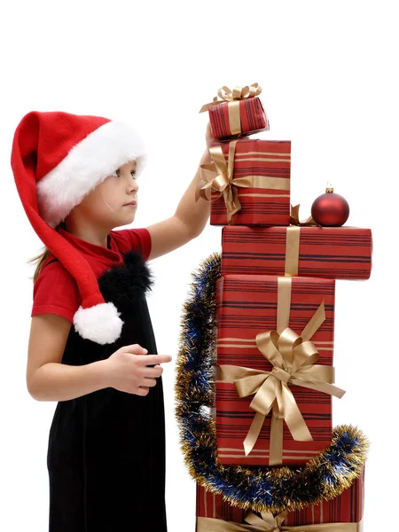 可爱的小女孩在圣诞老人的帽子与圣诞礼物在白色背景 — 图库照片